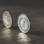 photo of two gold colored and silver colored coins standing on floor