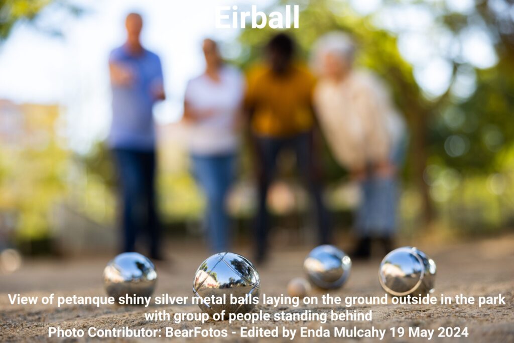 View of petanque shiny silver metal balls laying on the ground outside in the park with group of people standing behind